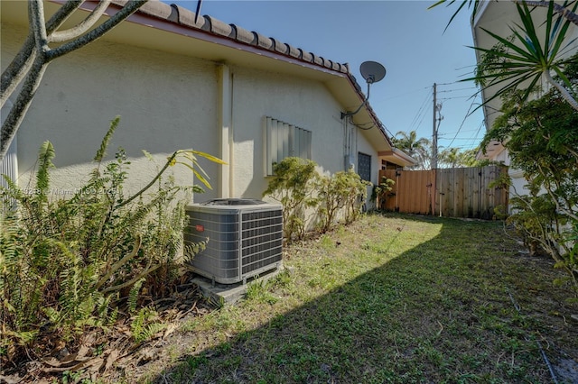 view of side of property with central AC unit and a lawn