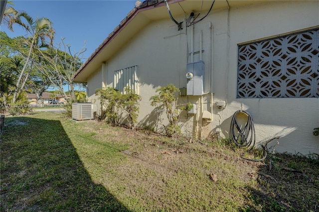 view of property exterior with central AC unit and a lawn