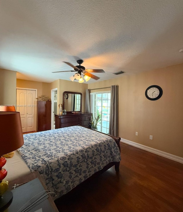 bedroom with a textured ceiling, ceiling fan, and dark hardwood / wood-style flooring