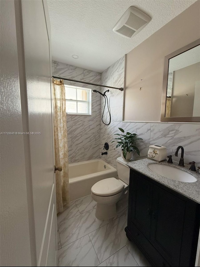 full bathroom featuring toilet, vanity, tile walls, shower / bathtub combination with curtain, and a textured ceiling