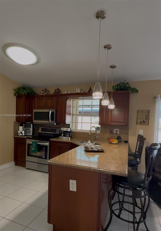 kitchen featuring pendant lighting, kitchen peninsula, sink, a healthy amount of sunlight, and stainless steel appliances