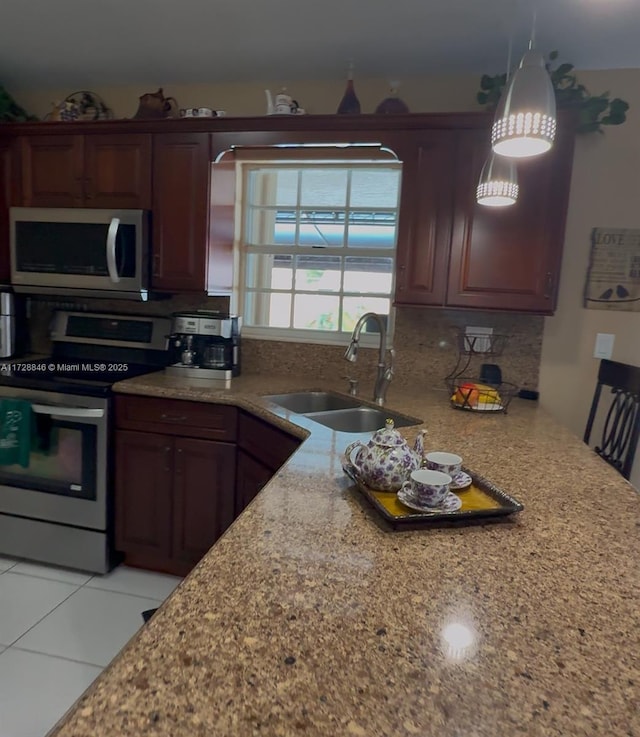 kitchen featuring light stone countertops, decorative light fixtures, stainless steel appliances, sink, and light tile patterned floors