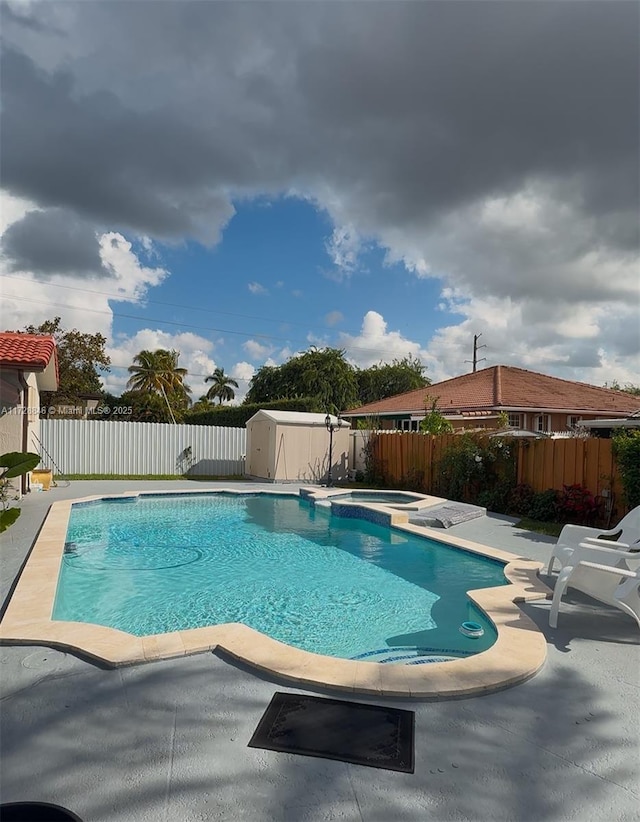 view of swimming pool with an in ground hot tub, a patio, and a storage unit