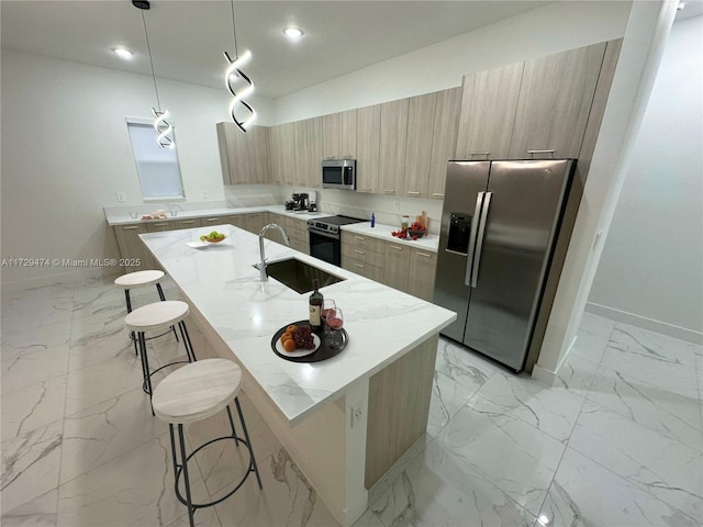 kitchen with a kitchen bar, stainless steel appliances, a kitchen island with sink, light stone countertops, and pendant lighting