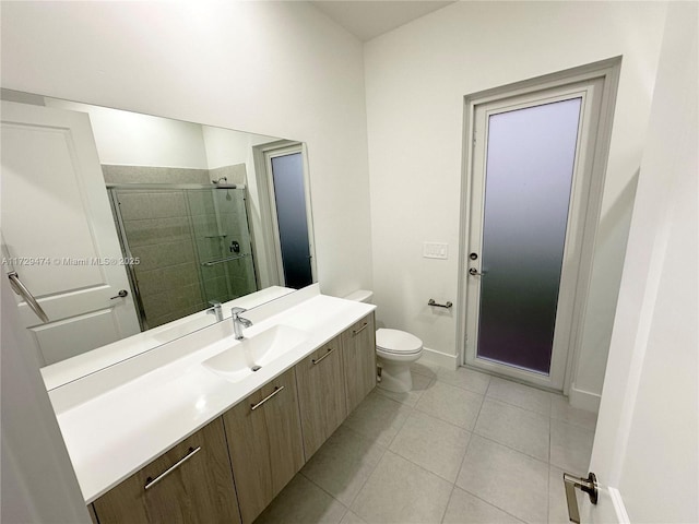 bathroom featuring tile patterned floors, toilet, a shower with door, and vanity