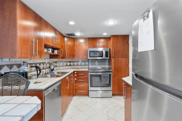300 Bayview Dr Unit 1503, Sunny Isles Beach, FL 33160 - kitchen featuring stainless steel appliances, tile countertops, tasteful backsplash, brown cabinetry, and open shelves