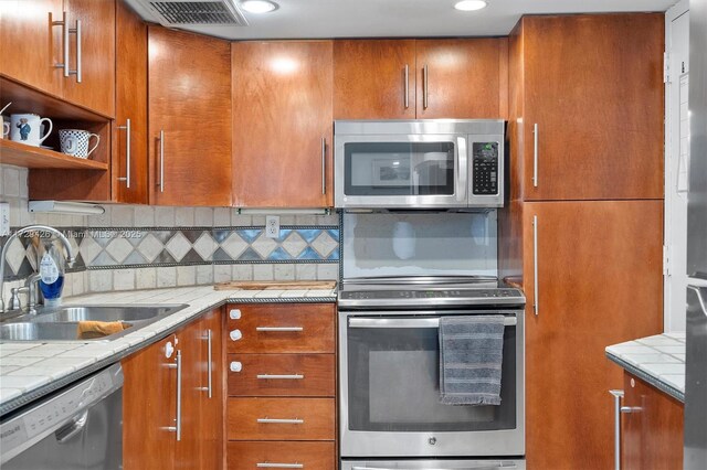 300 Bayview Dr Unit 1503, Sunny Isles Beach, FL 33160 - kitchen featuring appliances with stainless steel finishes, brown cabinetry, backsplash, open shelves, and recessed lighting