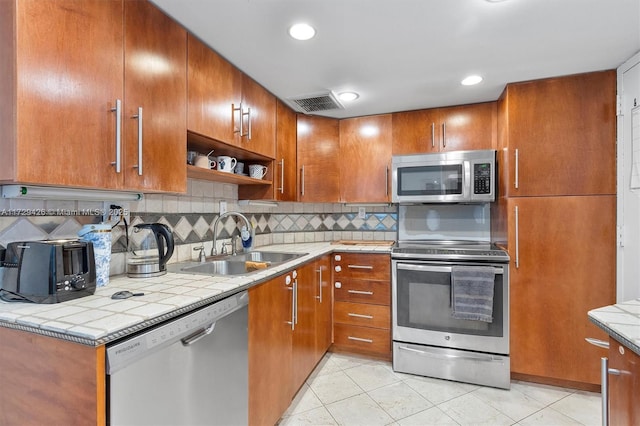 300 Bayview Dr Unit 1503, Sunny Isles Beach, FL 33160 - kitchen with stainless steel appliances, decorative backsplash, light tile patterned flooring, brown cabinets, and recessed lighting