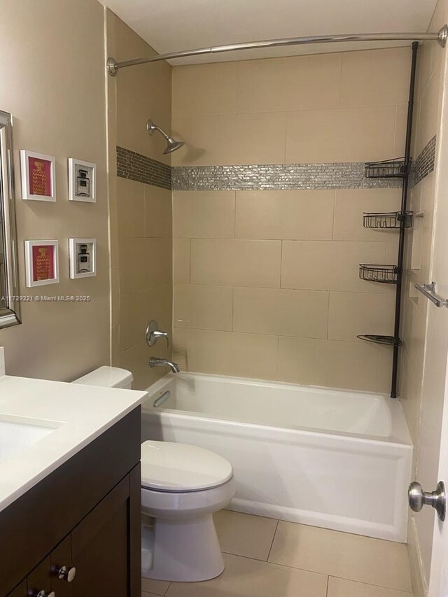 full bathroom featuring tile patterned flooring, vanity, tiled shower / bath combo, and toilet