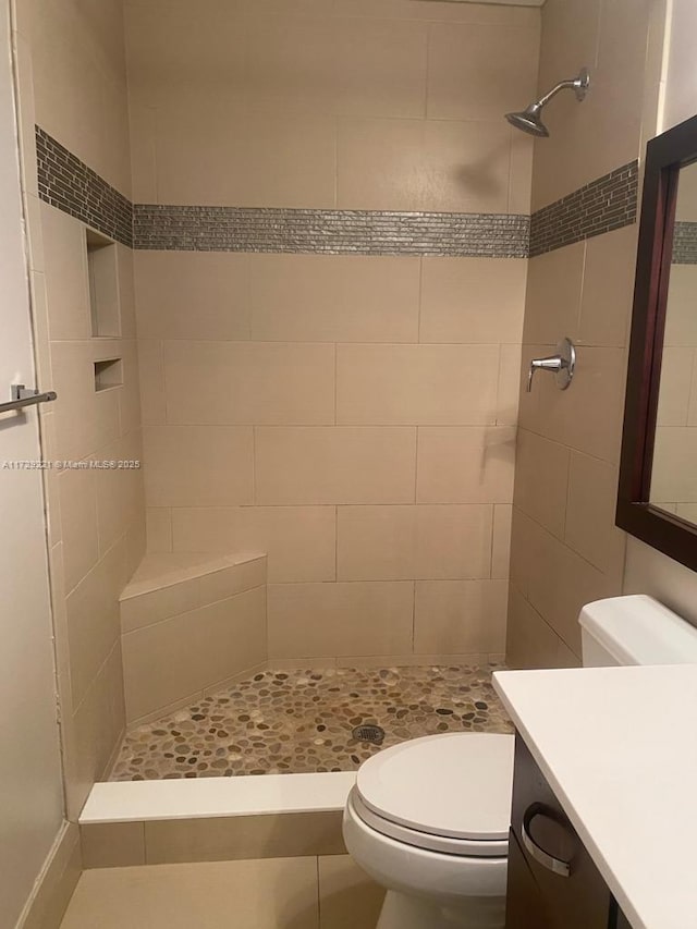 bathroom featuring tiled shower, vanity, and toilet