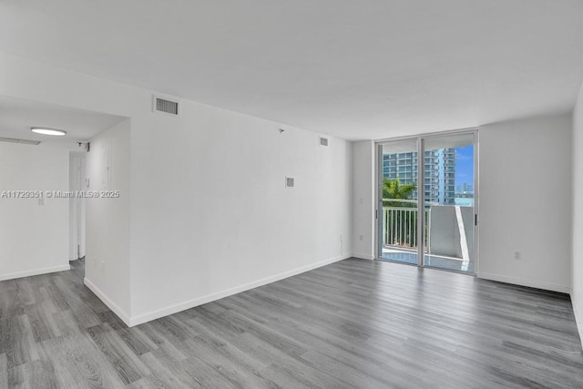 unfurnished room with light wood-type flooring and a wall of windows