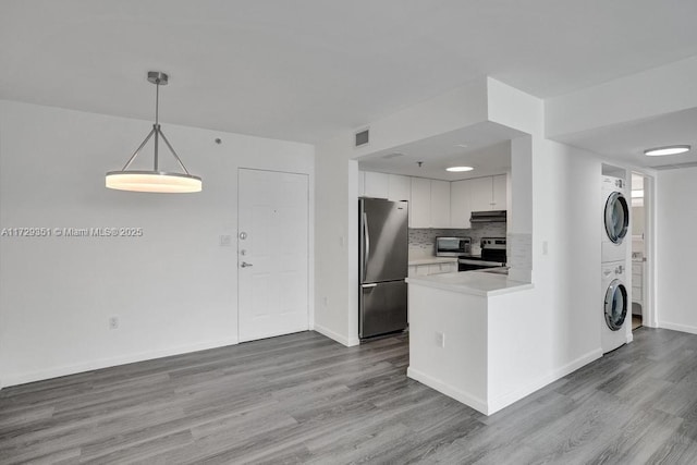 kitchen featuring white cabinets, decorative light fixtures, stainless steel appliances, stacked washer and dryer, and decorative backsplash