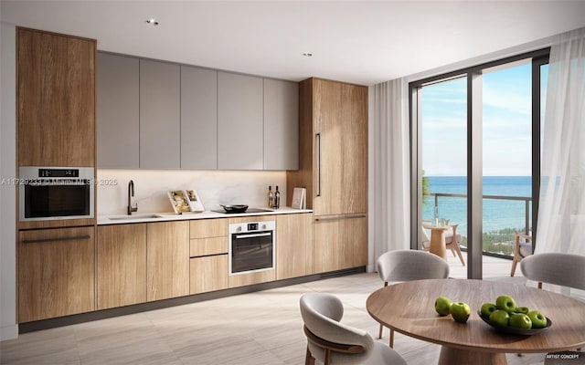 kitchen with stainless steel oven, a water view, expansive windows, and sink