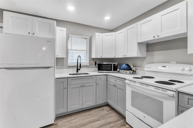 kitchen featuring white cabinets, sink, white appliances, and light hardwood / wood-style flooring