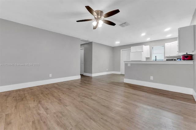 unfurnished living room featuring ceiling fan and light wood-type flooring