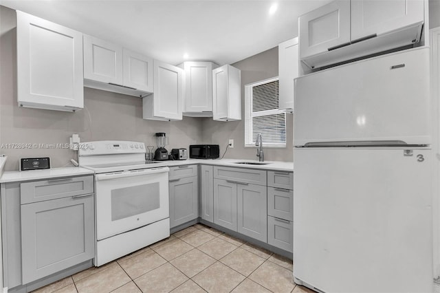 kitchen with light tile patterned floors, sink, white cabinetry, and white appliances