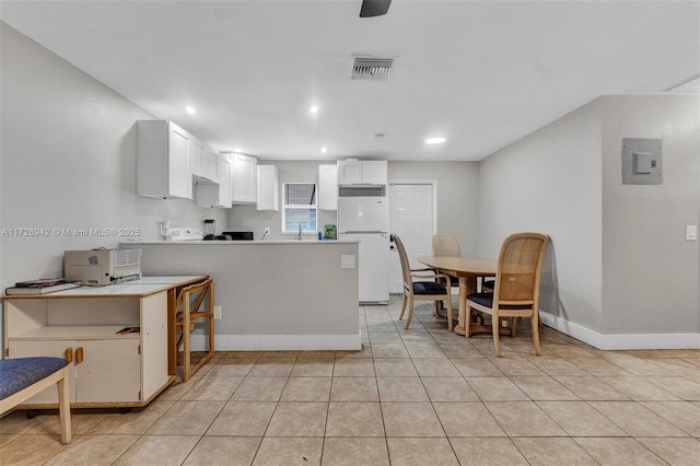 kitchen featuring white cabinets, kitchen peninsula, light tile patterned floors, and white fridge