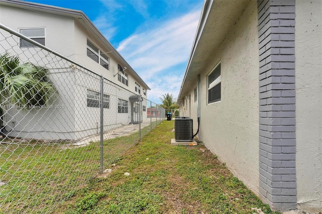 view of side of property featuring a lawn and central AC