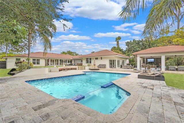 view of pool with an outdoor living space, a patio, and ceiling fan