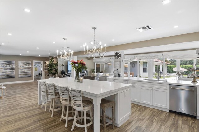 kitchen featuring white cabinetry, a kitchen breakfast bar, a kitchen island, decorative light fixtures, and stainless steel dishwasher