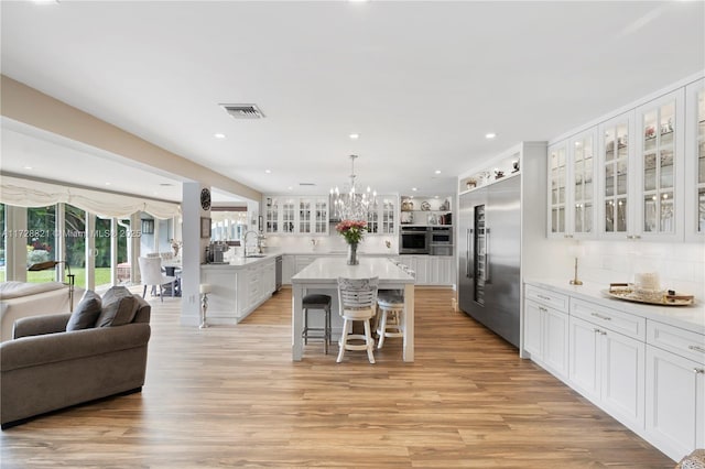 kitchen with a breakfast bar area, appliances with stainless steel finishes, a kitchen island, pendant lighting, and white cabinets