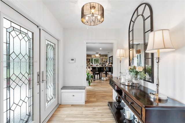 foyer entrance with french doors, an inviting chandelier, and light hardwood / wood-style flooring