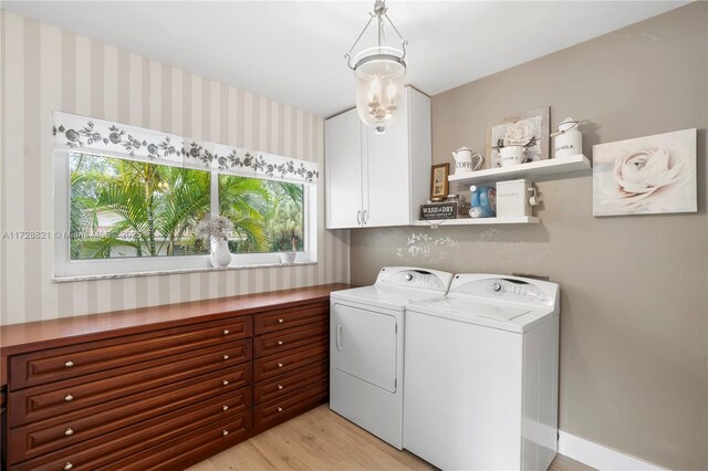 clothes washing area with cabinets, light hardwood / wood-style floors, and washing machine and dryer