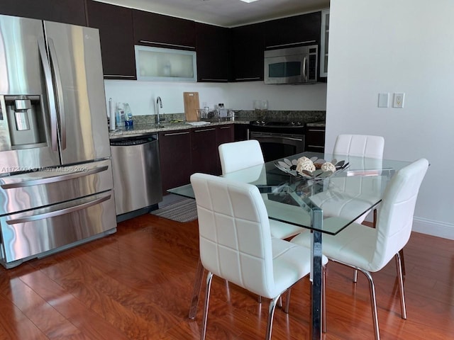 kitchen featuring stone counters, appliances with stainless steel finishes, dark hardwood / wood-style flooring, and sink