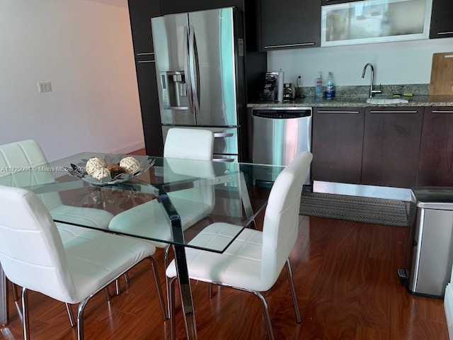 kitchen with light stone countertops, sink, hardwood / wood-style flooring, and stainless steel appliances