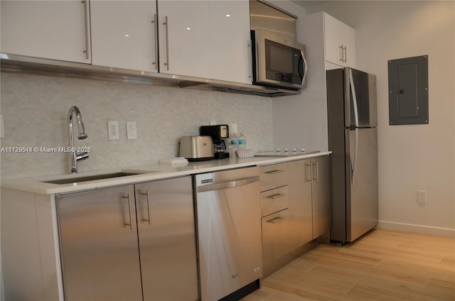 kitchen featuring stainless steel appliances, sink, white cabinets, and electric panel