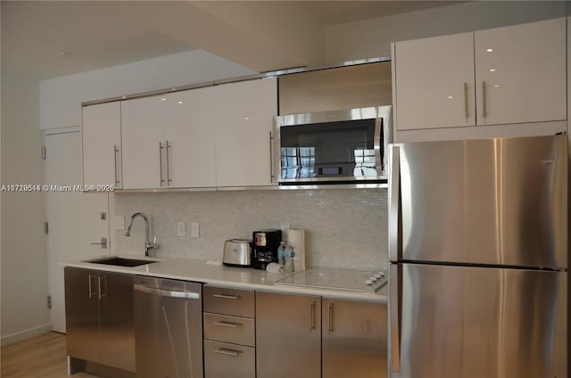 kitchen featuring white cabinets, appliances with stainless steel finishes, sink, and tasteful backsplash