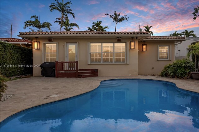 back house at dusk featuring a patio area