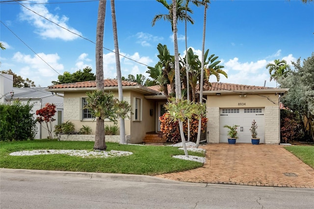 mediterranean / spanish home with a garage and a front lawn