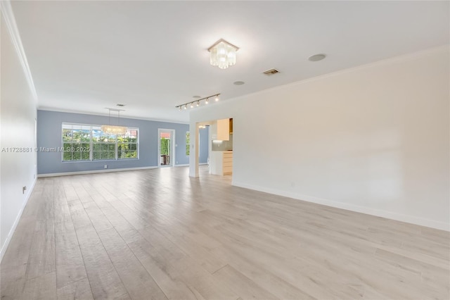 empty room featuring an inviting chandelier, rail lighting, ornamental molding, and light hardwood / wood-style floors