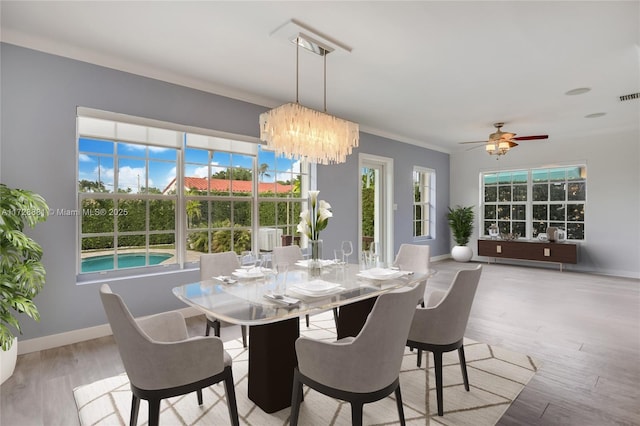 dining space with an inviting chandelier, ornamental molding, and light hardwood / wood-style floors