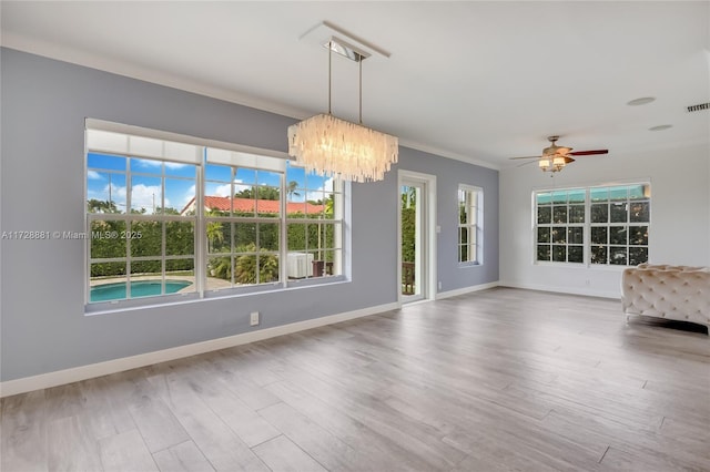 interior space with hardwood / wood-style floors, crown molding, and ceiling fan with notable chandelier