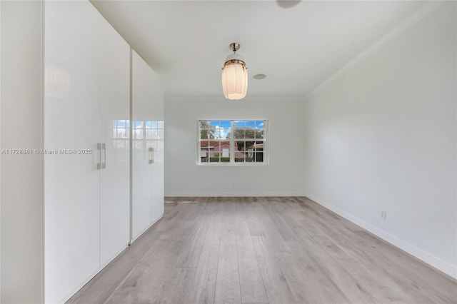 empty room with crown molding and light wood-type flooring