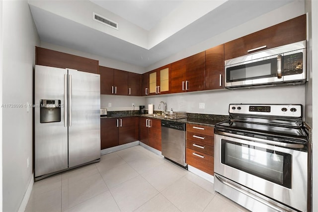 kitchen featuring light tile patterned flooring, sink, stainless steel appliances, and dark stone countertops