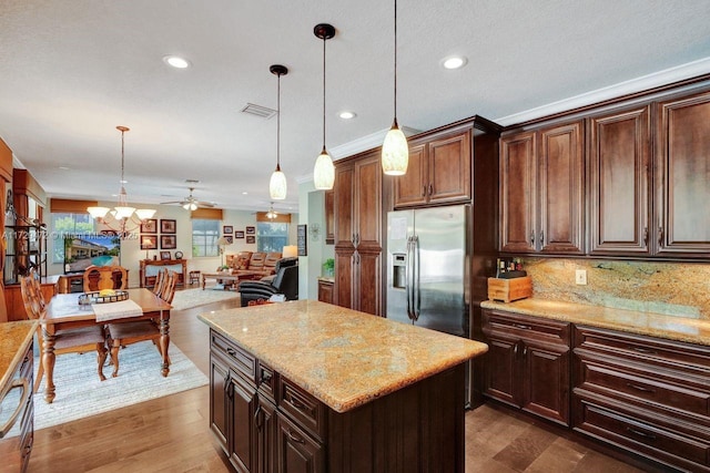 kitchen with a kitchen island, pendant lighting, dark brown cabinets, and stainless steel fridge