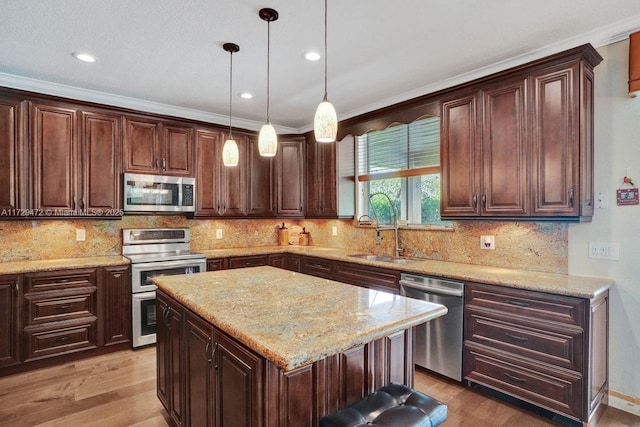 kitchen featuring stainless steel appliances, dark brown cabinets, a kitchen island, pendant lighting, and sink