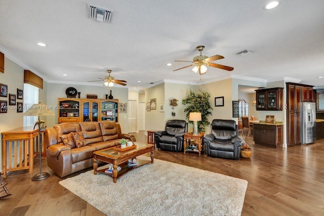 living room featuring ceiling fan, wood-type flooring, and crown molding