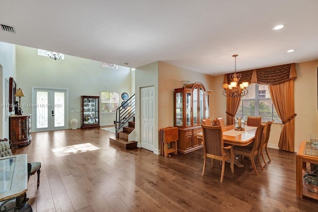 dining space with dark wood-type flooring, french doors, plenty of natural light, and an inviting chandelier