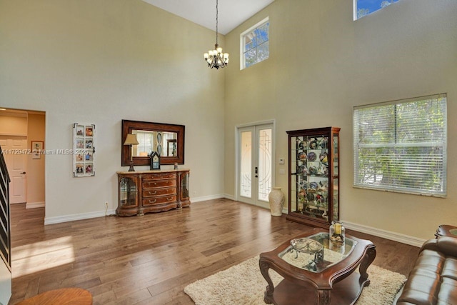 living room featuring dark wood-type flooring, an inviting chandelier, and a high ceiling