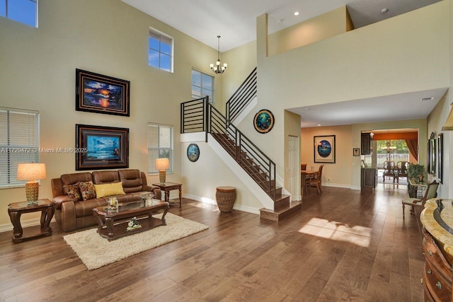 living room with a notable chandelier, a high ceiling, and hardwood / wood-style floors