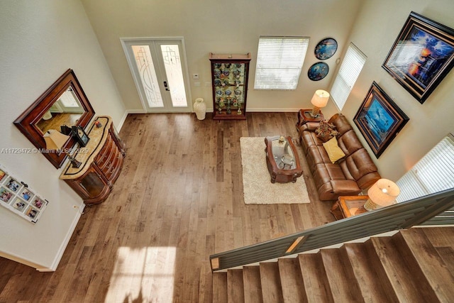 living room with a towering ceiling, light hardwood / wood-style floors, and french doors