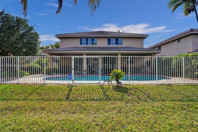 rear view of property featuring a lawn and a fenced in pool