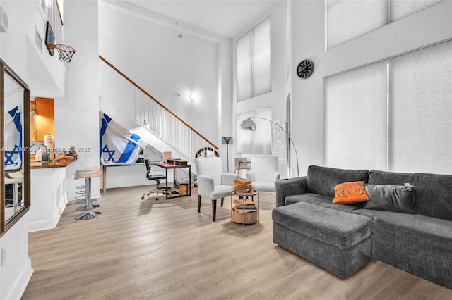 living room featuring light hardwood / wood-style flooring and a towering ceiling