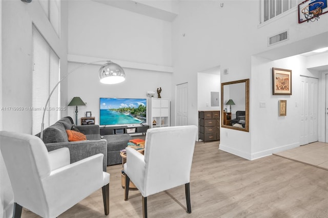 living room with a towering ceiling and light wood-type flooring