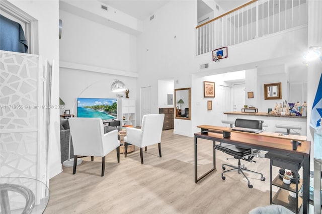 office space with a high ceiling and light hardwood / wood-style flooring