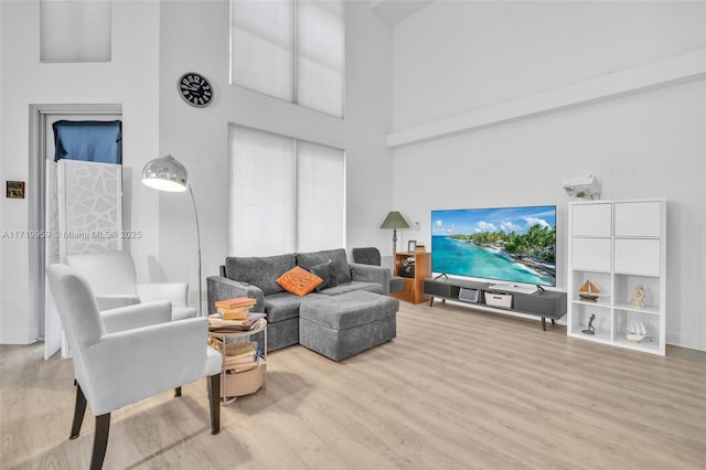 living room with a towering ceiling and light hardwood / wood-style flooring